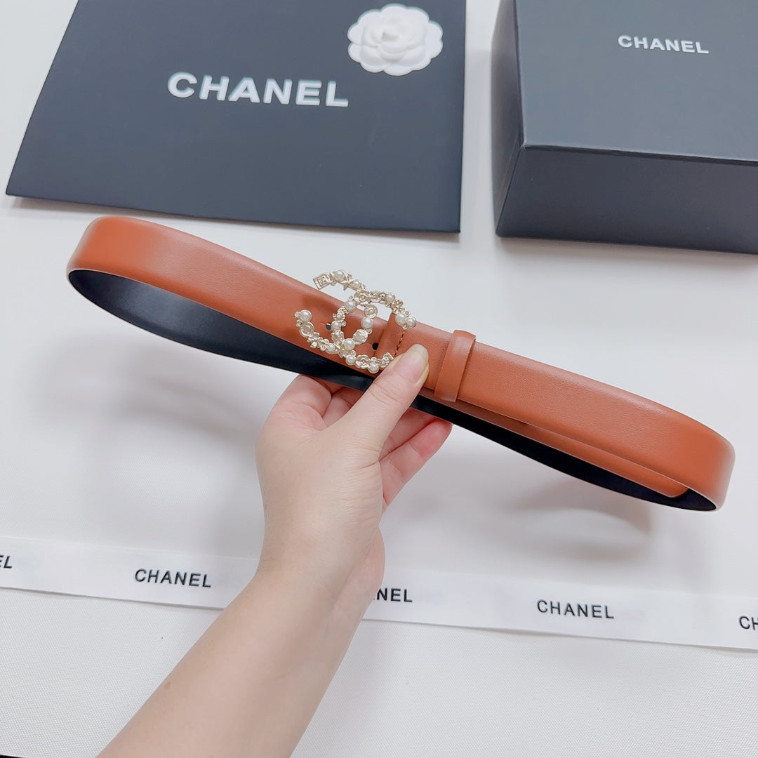Orange leather belt with silver-tone embellished buckle, held in hand.