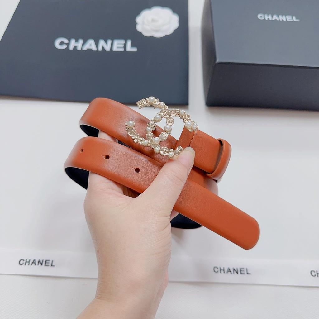 Orange leather belt with rhinestone-style CC buckle, held up for view.