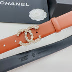 Orange belt close-up: silver embellished buckle and perforation holes, black underside.