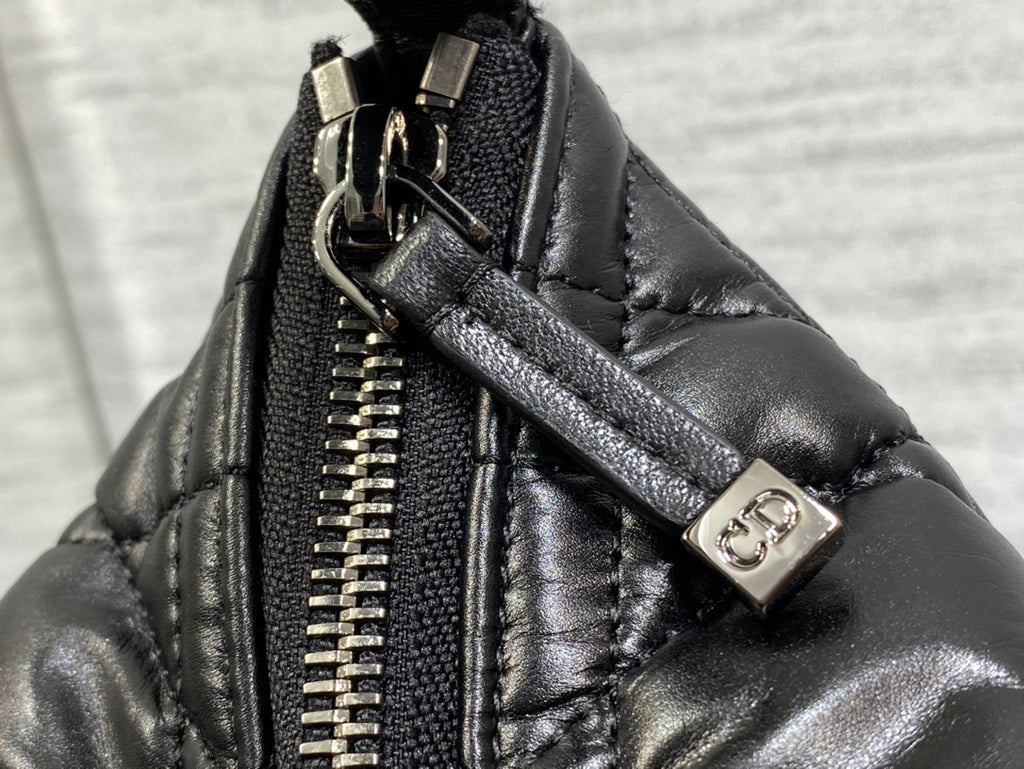 Black Dior bag close-up: gold-tone zipper and logo snap hardware