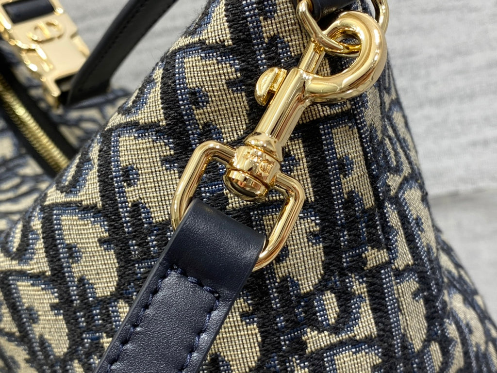 Dior bag close-up of gold lobster clasp with navy leather strap and Dior print