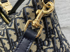 Dior bag close-up of gold lobster clasp with navy leather strap and Dior print