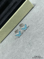 Butterfly stud earrings pair on light fabric, blue enamel wings with silver-tone setting.