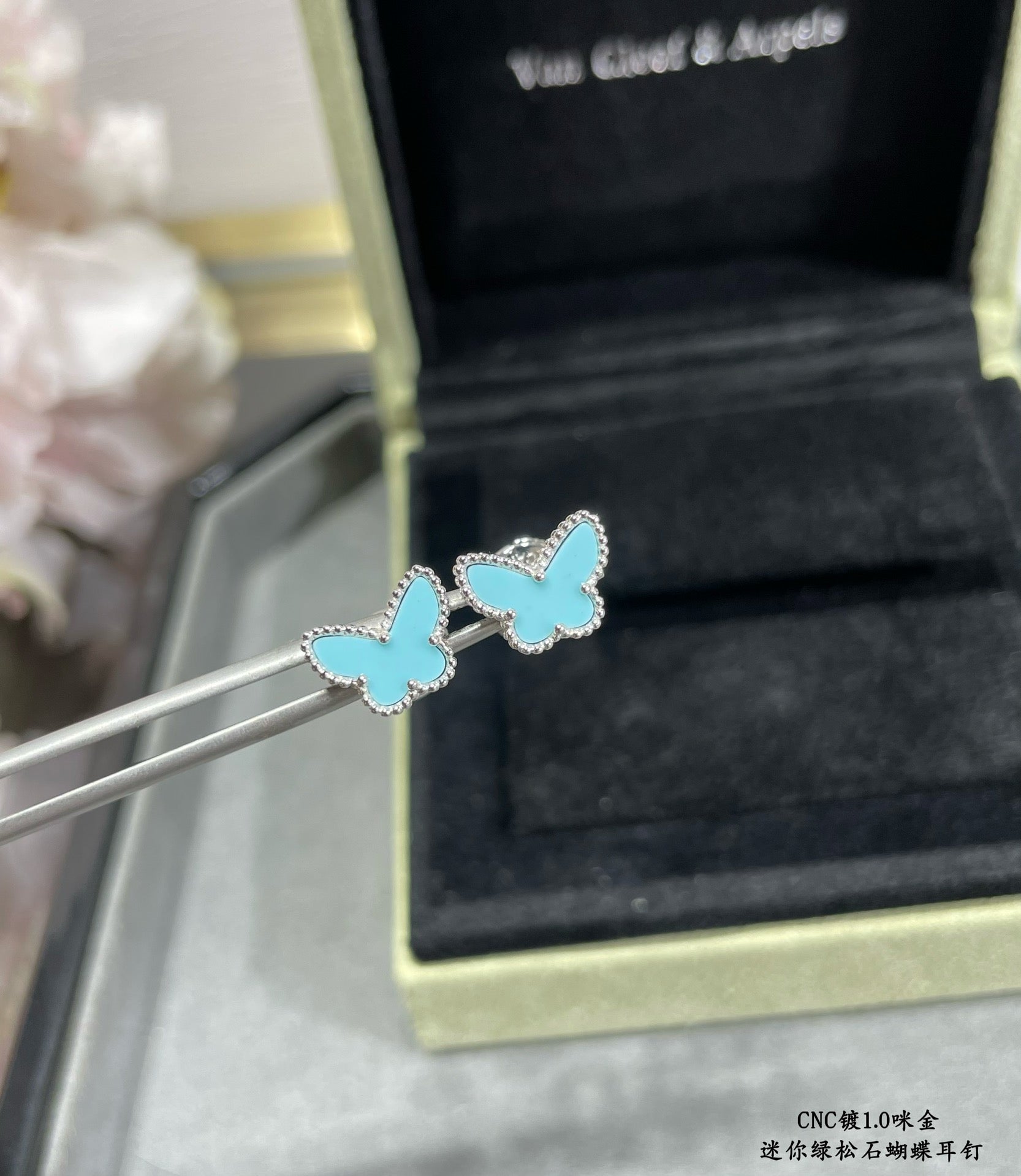 Blue butterfly stud earrings held on tool, silver-tone frames with light enamel details.