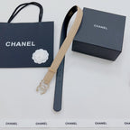 Beige Chanel belt with gold buckle and dangling rhinestone CC charm; black underside