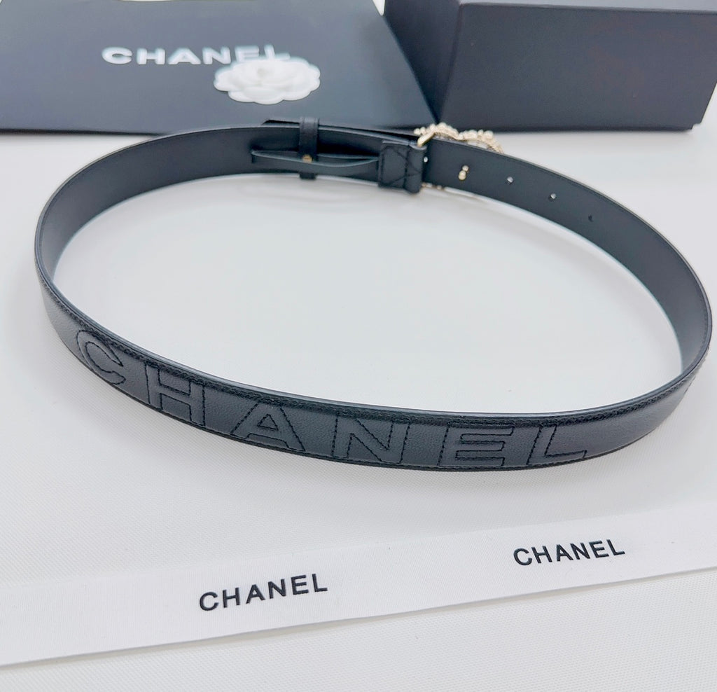 Chanel belt with dark strap featuring repeating 'CHANEL' logo pattern and gold buckle