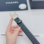Chanel belt held in hand; dark blue embossed strap with ornate gold and pearl clasp