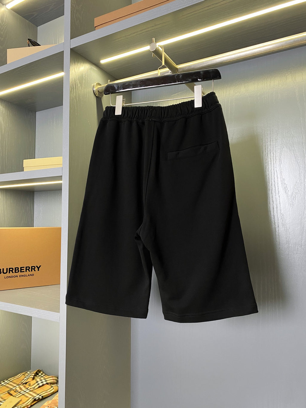 Black Burberry shorts hanging on a rack with relaxed straight legs