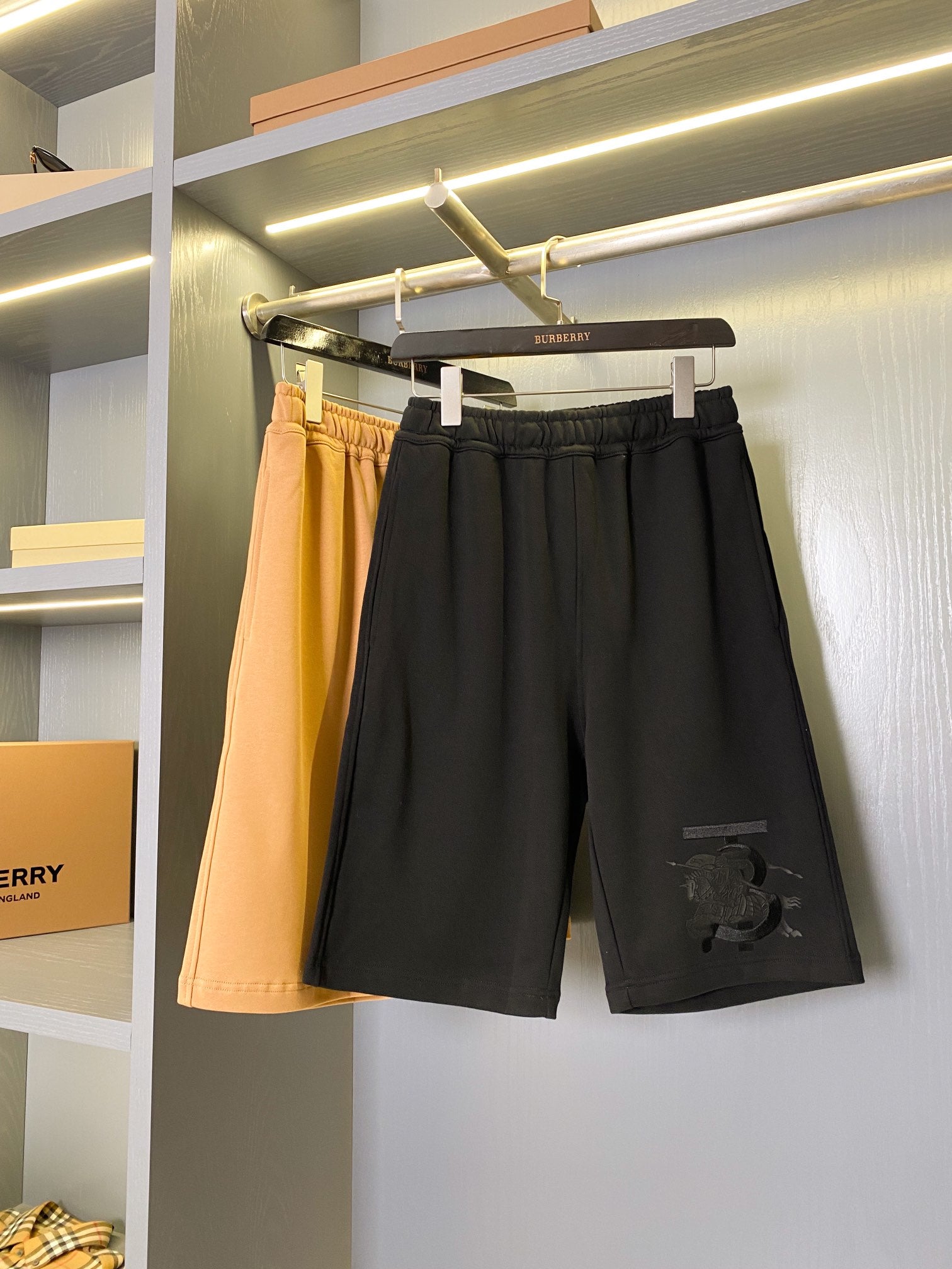 Black and tan Burberry shorts on a rack, elastic waistbands visible