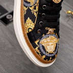 Versace sneakers detail, black lace-up with gold medallion artwork and gold hardware