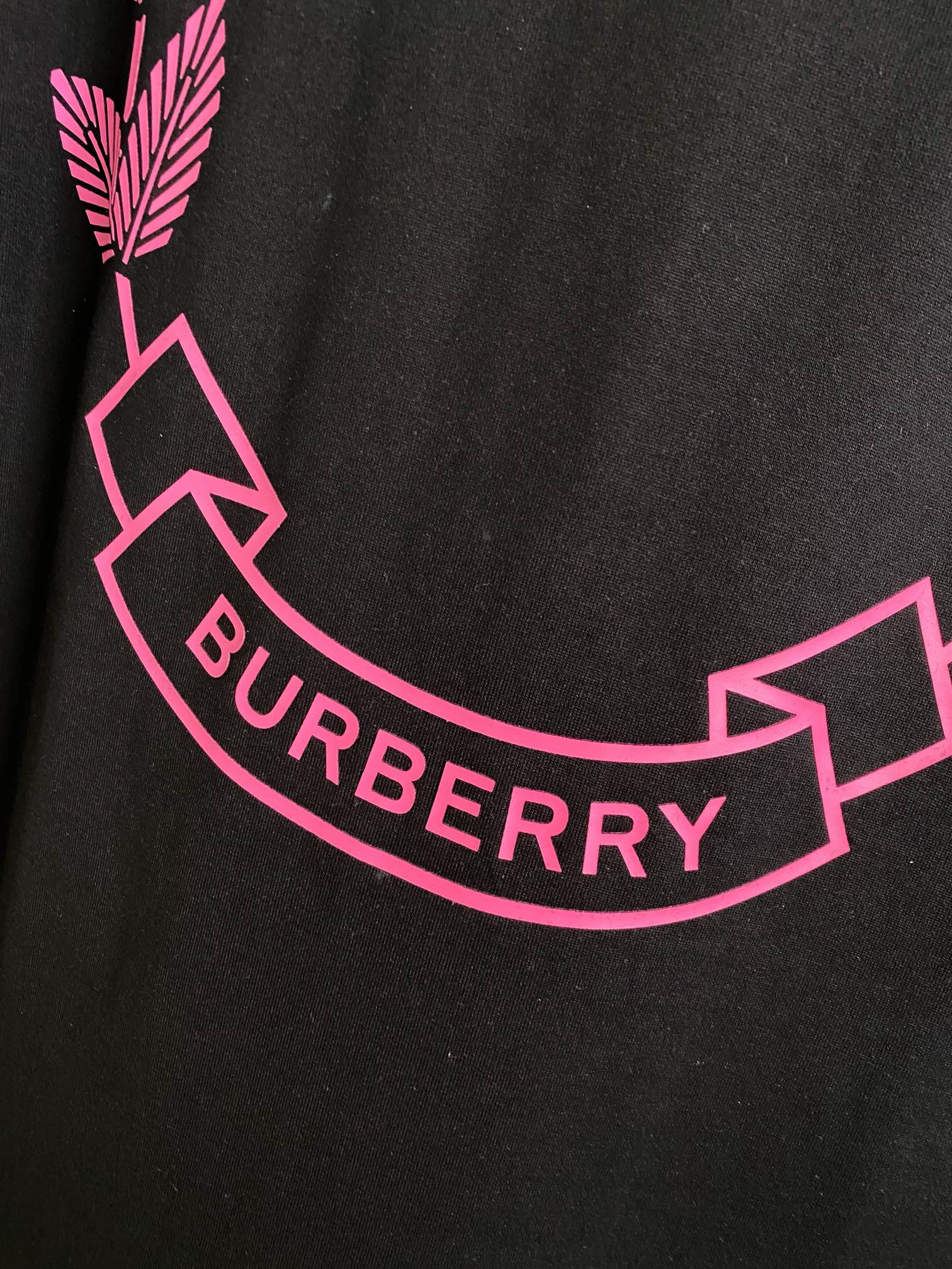 Black T-shirt detail with pink laurel graphic and curved BURBERRY text