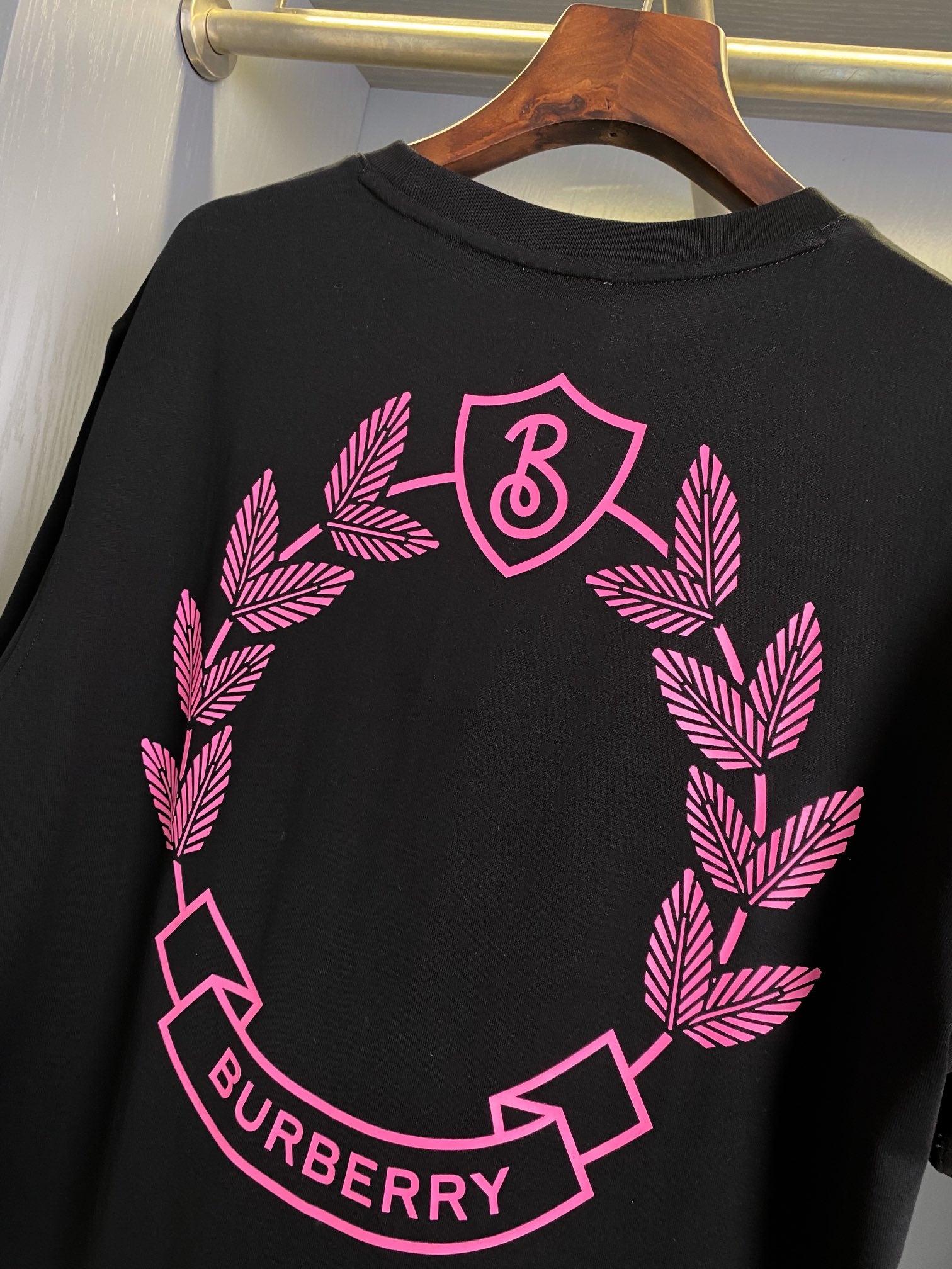 Black short-sleeve T-shirt close-up of pink wreath and B logo graphic