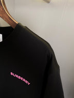 Black T-shirt shoulder close-up with small pink BURBERRY text