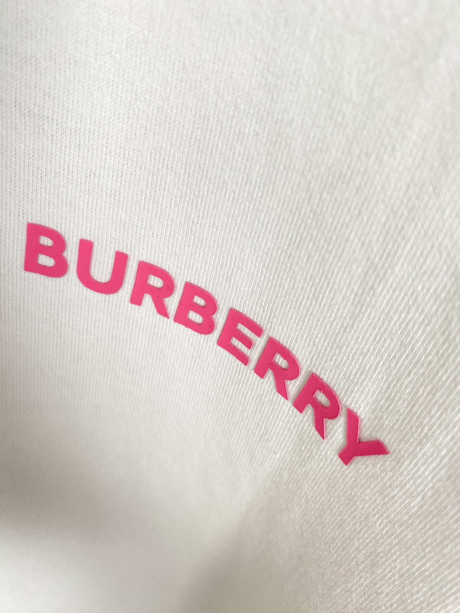 White T-shirt fabric close-up of pink BURBERRY lettering