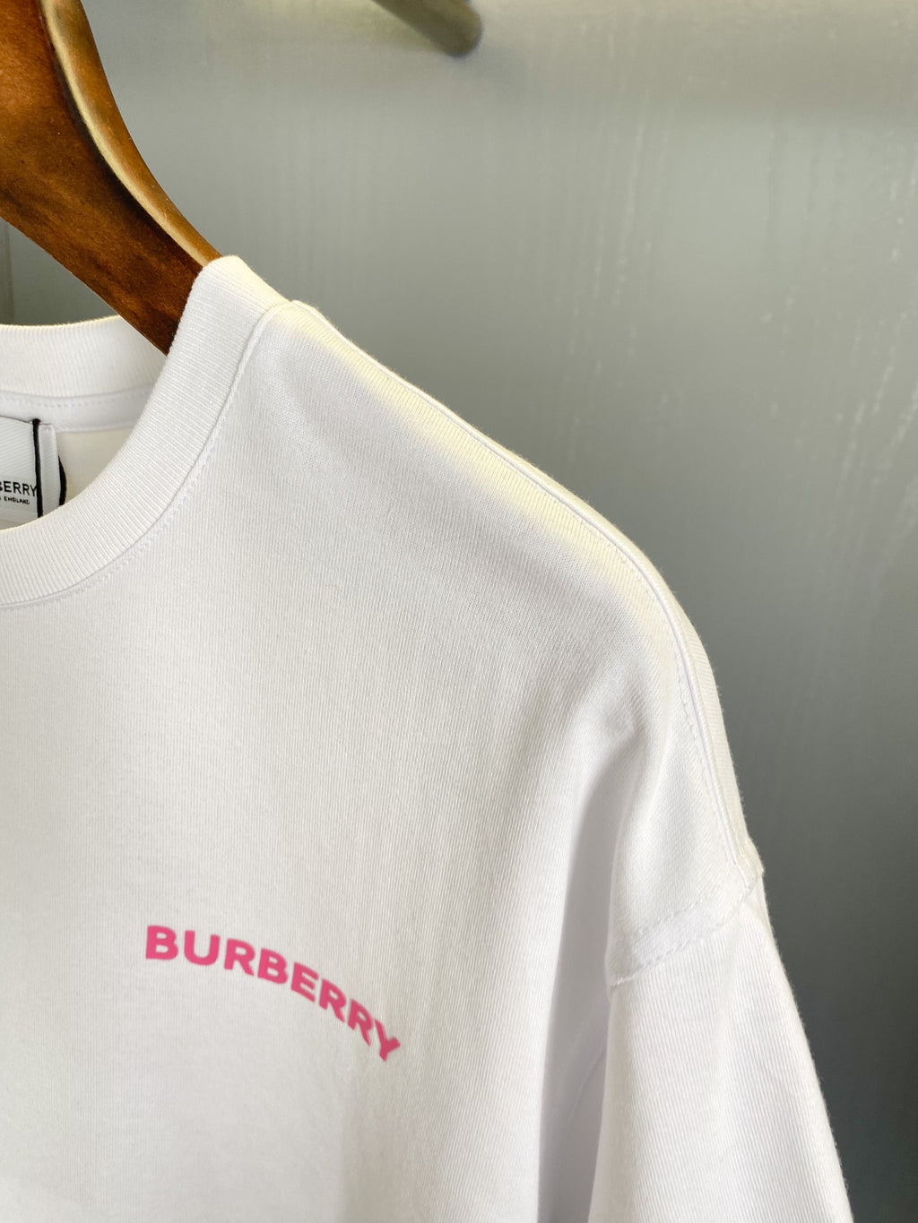 White short-sleeve T-shirt neckline with small pink Burberry text, short sleeves