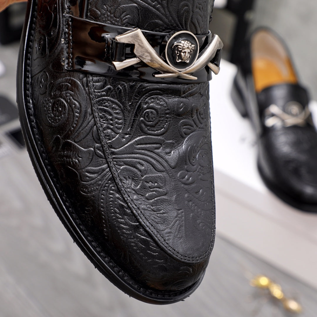 Close-up of black embossed leather loafer with silver buckle and medallion.