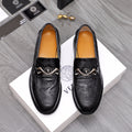 Black embossed leather loafers with silver buckle and emblem detail.