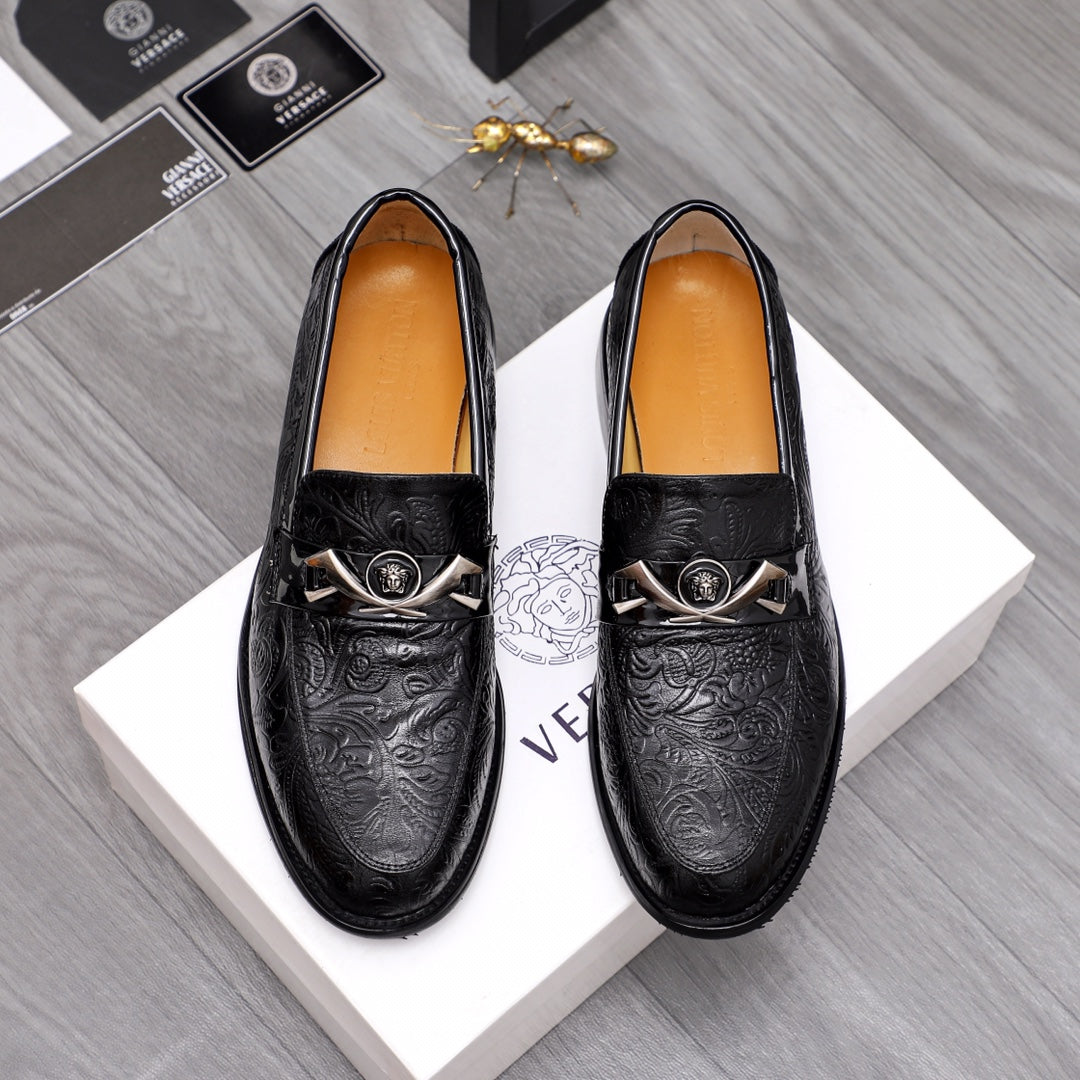 Black embossed leather loafers with silver buckle and emblem detail.