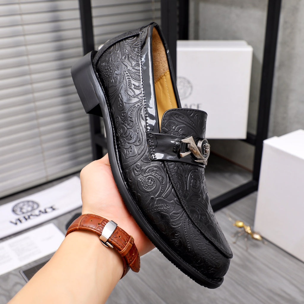 Black embossed leather loafer with silver buckle, side view held in hand.