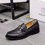 Black embossed leather loafers, side view, slip-on with silver buckle detail.