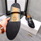 Black leather loafer sole with Versace logo; tan insole visible.