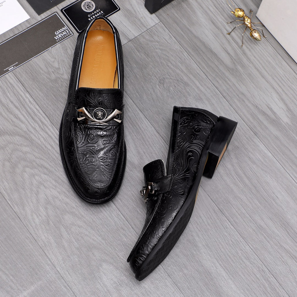 Pair of black embossed leather loafers with silver buckles and tan lining.