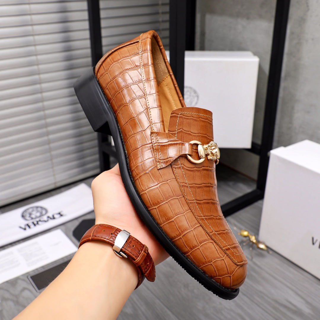 Versace luxury shoes, brown leather loafer with gold bit buckle; shown on hand