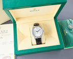 Rolex watch in presentation box, black leather strap, silver case, white dial
