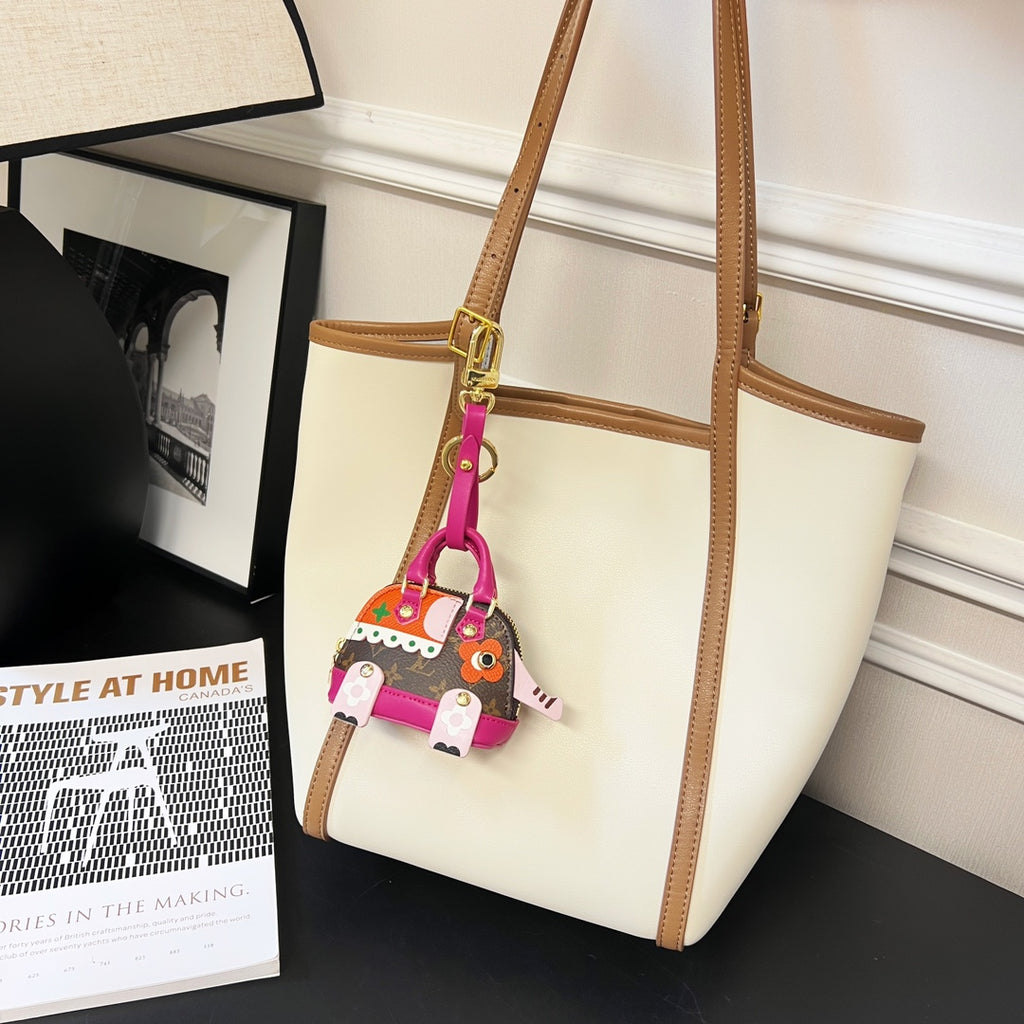 Louis Vuitton mini handbag charm hanging from a tan tote strap, magenta accents and gold hardware