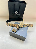 Leather belt with gold baroque print and silver Medusa buckle on dark navy leather strap.