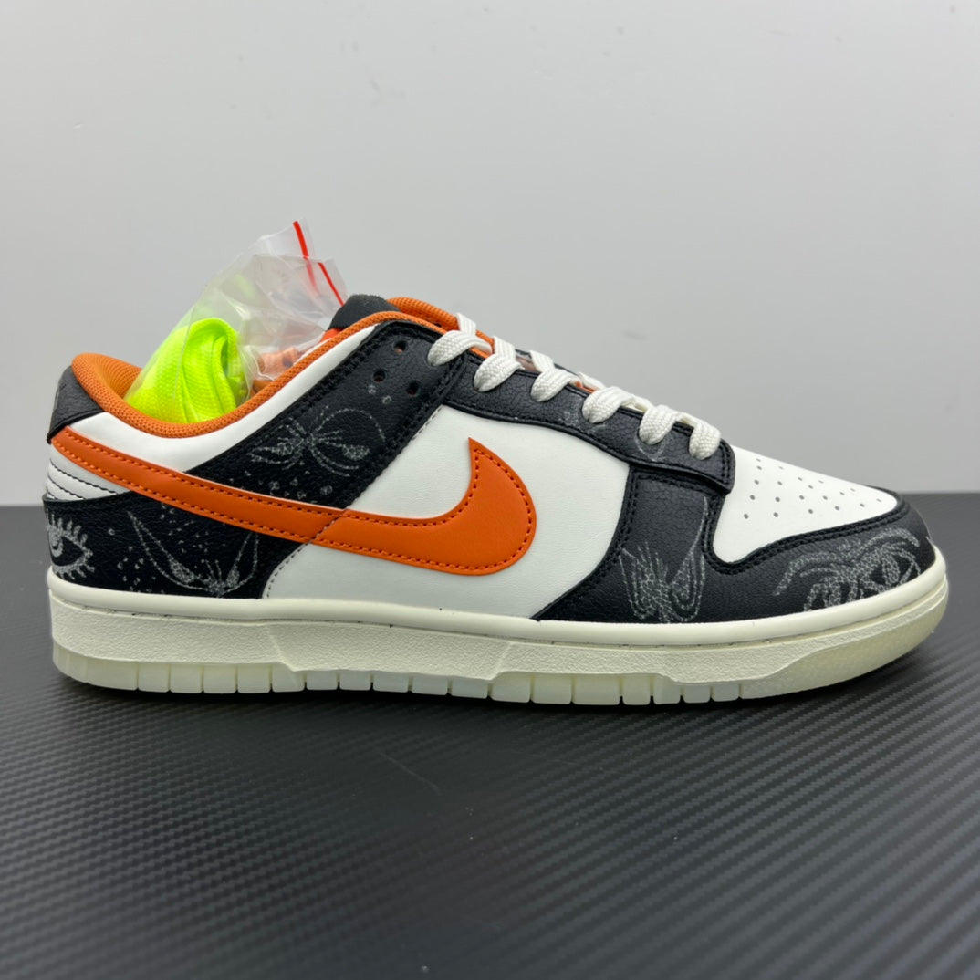 Low-top sneakers with white upper, black toe and side, orange Swoosh, white laces.