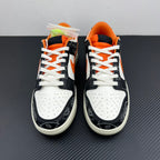Pair of low-top sneakers in black and white with orange accents, white laces, padded collar.