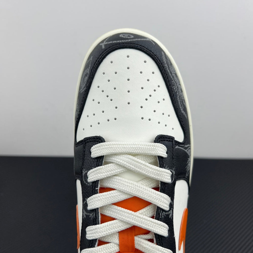 Low-top sneakers front view: white toe box, black overlays, orange inner tongue, white laces.