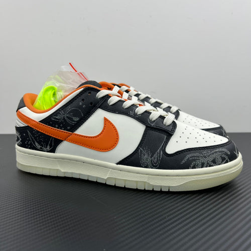 Low-top sneakers with white and black panels, orange Swoosh, white laces, chunky sole.