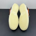 Low-top sneakers bottom view with pale yellow outsole treads; black and orange upper.