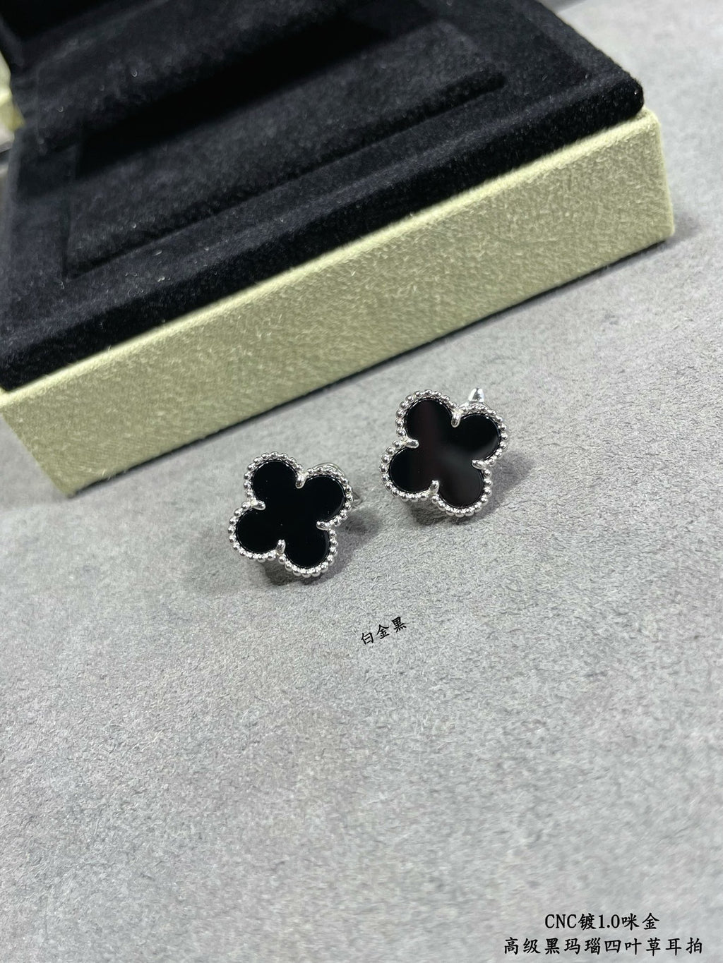 Van Cleef & Arpels quatrefoil stud earrings close-up, dark enamel with silver outline