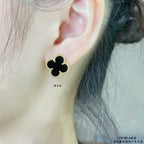Van Cleef & Arpels quatrefoil stud earrings on ear, black enamel with gold trim