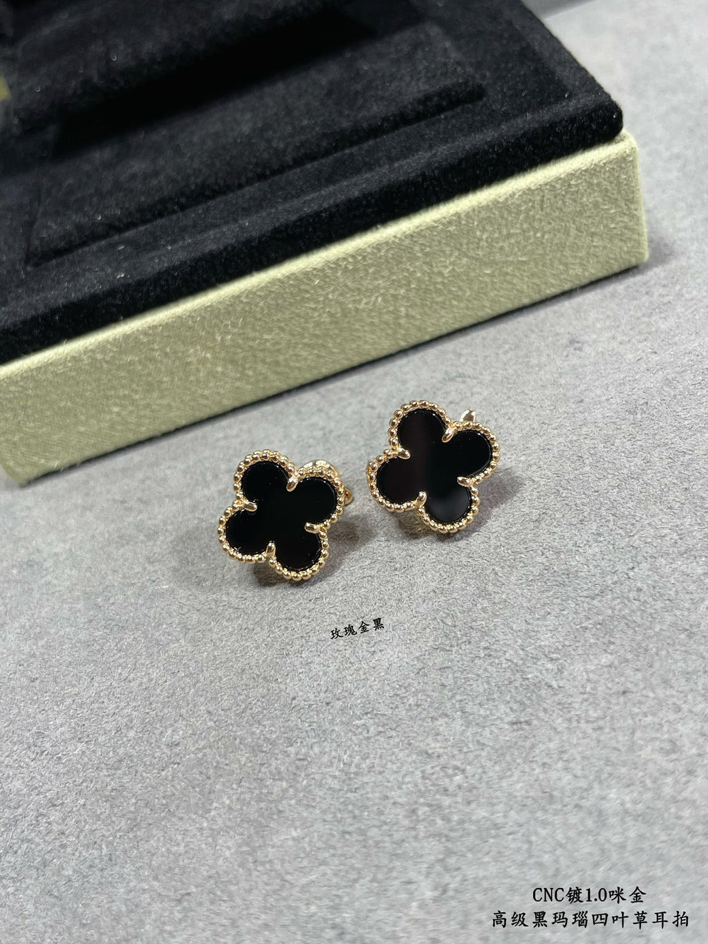 Van Cleef & Arpels quatrefoil stud earrings close-up, dark enamel with gold outline