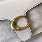 Coah bag detail, large gold O-ring closure on white flap with burgundy stitching