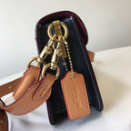 Navy handbag top with gold hardware, tan straps, and leather keychain tag