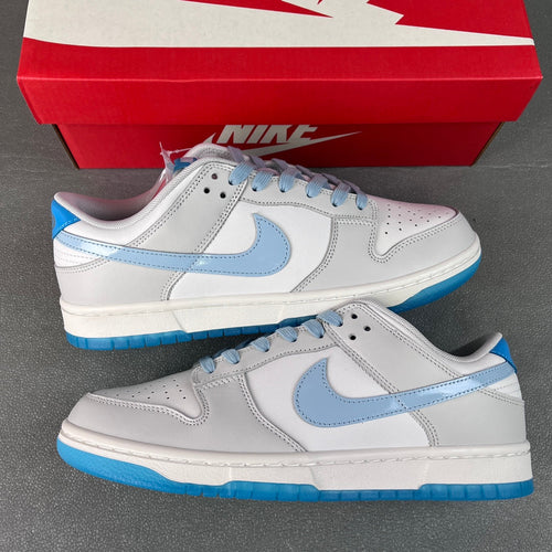 Pair of white low-top Nike Dunk SB sneakers with light blue laces and swooshes