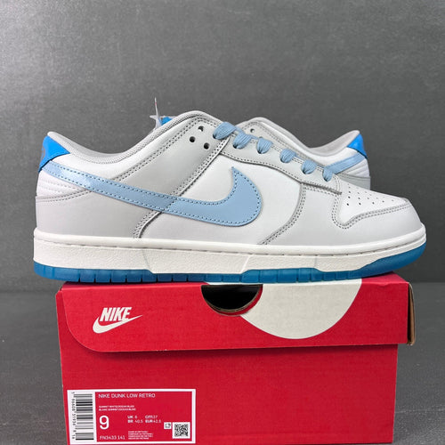 White low-top Nike Dunk SB sneaker with light blue swoosh and blue outsole trim