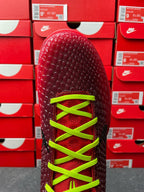 Red sneaker upper with neon green lace eyelets, rounded toe, top view.