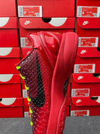 Red sneaker with black side panel and neon green laces, three-quarter top view.
