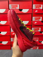 Red basketball shoe with black stripe and neon green laces, angled side view.