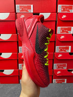 Red sneaker with black side panel, neon green lace accents, angled side view.