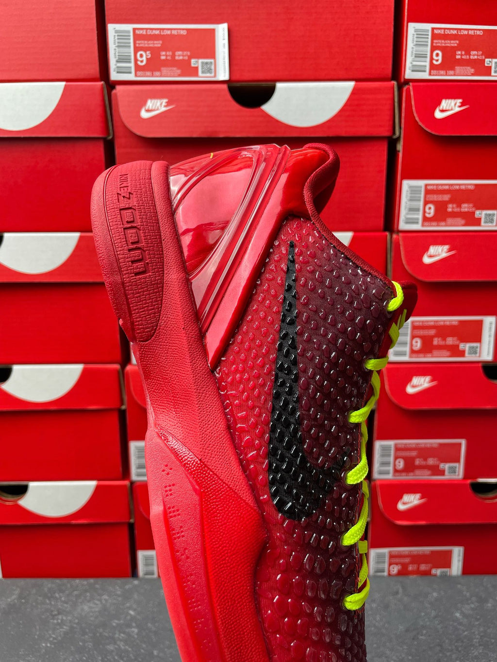 Red basketball shoe showing textured upper, black stripe, neon green laces, heel view.