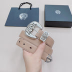 Chrome belt held in hand with beige strap and silver ornate buckle