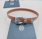 Brown leather belt on display with ornate silver buckle and metal keeper accents