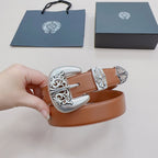 Brown leather belt held in hand showing ornate silver buckle and engraved accents